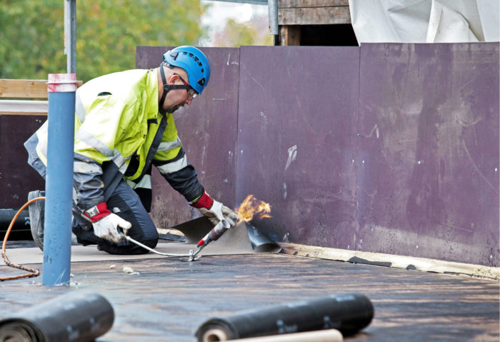 Florim Bajrami asentaa k&auml;&auml;nnetyn katon kolminkertaista kumibitumikermi&auml;.