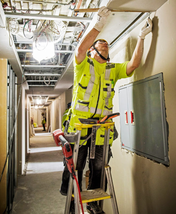 Juha Nevalainen asentaa kipsilevy&auml; k&auml;yt&auml;v&auml;n alakattoon.